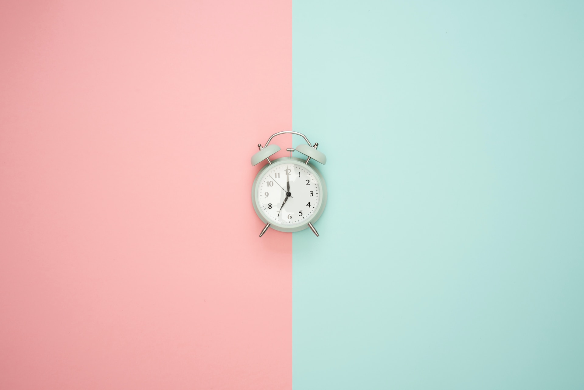 ピンクと淡いブルーの壁にベル目覚ましが真ん中にある