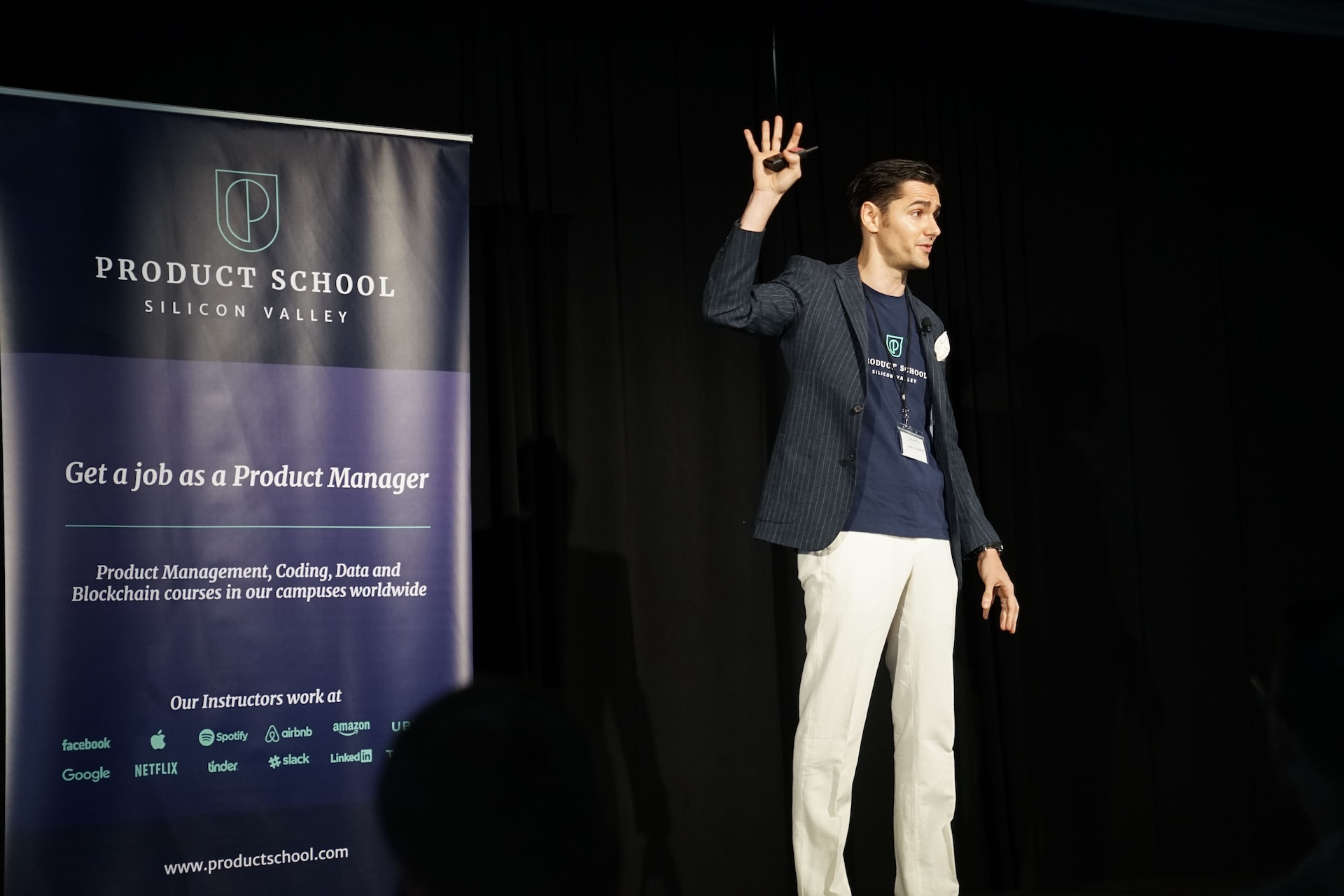 ステージで観衆に質問を求める男性